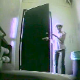 A hidden camera mounted behind a toilet captures a woman peeing while standing over a toilet. No audio.